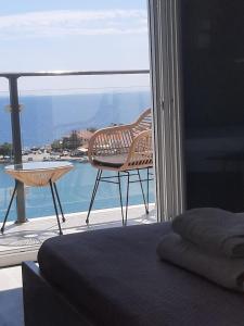 una camera da letto con balcone affacciato sull'oceano di OLYMPIADA View 1 a Pythagóreion
