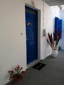 une porte bleue dans un mur blanc avec un vase avec stylos dans l'établissement Welcome to Giouli's home !, à Elafonisos