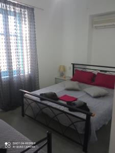- une chambre avec un lit doté d'oreillers rouges et une fenêtre dans l'établissement Welcome to Giouli's home !, à Elafonisos