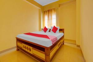 una camera da letto con un letto con cuscini rossi e una finestra di OYO Flagship Hotel Sweet And Soul a Jamshedpur