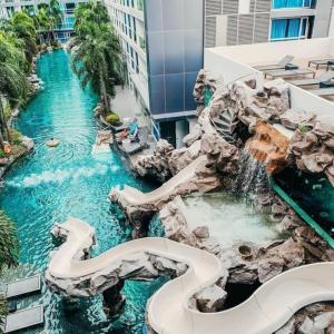 a water slide in a resort with a waterfall at Plein centre-ville : appartement d'angle moderne in Pattaya Central