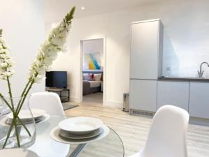 a white living room with a glass table and white chairs at Altitude at Fleet Heights Apartment One in Fleet