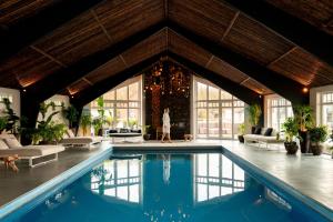 a woman walking in a room with a swimming pool at Noordzee, Hotel & Spa in Cadzand-Bad