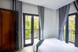 a bedroom with a bed and large windows at Casa Vanilla Mang Den in Kon Von Kla