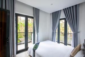 a bedroom with a bed and large windows at Casa Vanilla Mang Den in Kon Von Kla