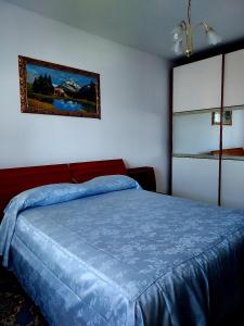 ein Schlafzimmer mit einem blauen Bett und einem Bild an der Wand in der Unterkunft Tina'home in Selcetta