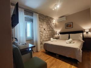 1 dormitorio con cama y pared de piedra en Carol Rooms, en Trogir