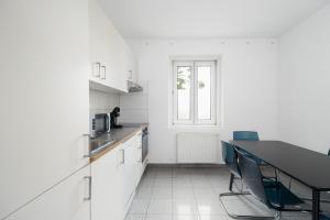cocina con armarios blancos, mesa y sillas en Apartment Kröllgasse I contactless check-in, en Viena