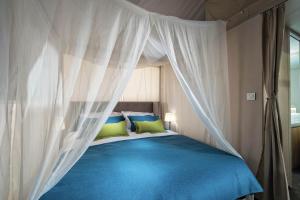 een slaapkamer met een blauw bed en een baldakijn bij Banki Green Istrian Village - Holiday Homes & Glamping Tents in Bašići