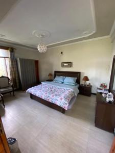 Un dormitorio con una cama grande y una lámpara de araña. en Sikandar Bagh Cottages en Nathia Gali