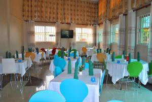 a banquet hall with tables and chairs and a tv at Pearl Highway Hotel Kibuye Kampala in Kampala