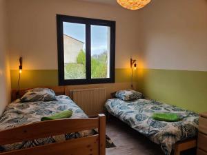 Un dormitorio con dos camas y una ventana. en La maison de Virginie, en Sisteron