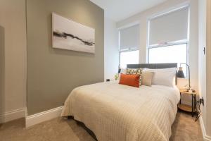 a bedroom with a bed and two windows at Modern 1 Bedroom Flat near Leeds City with Free Parking, Ideal for Contractors & Long Stays - NordStay in Hunslet