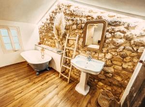 ein Badezimmer mit einer Steinmauer, einem Waschbecken und einer Badewanne in der Unterkunft Le Clos Bohème - Baron in Baron
