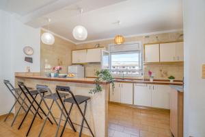 una cocina con armarios blancos y taburetes de bar en Basic Comfort Casa al canal Porto Fino 0153, en Empuriabrava