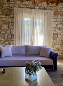 a living room with a purple couch and a stone wall at Villa Maria 1 in Gliki