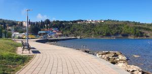 a bench on a sidewalk next to a body of water at Apartment LAGUNA 37 in Izola