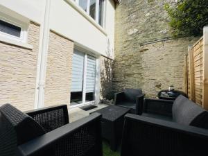 a patio with black chairs and a brick building at L'Alma 8 : Le Calme au Coeur de Cherbourg in Cherbourg en Cotentin