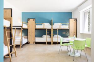 ブリンディジにあるOstello della Gioventù Brindisiの二段ベッド、テーブル、椅子が備わる客室です。