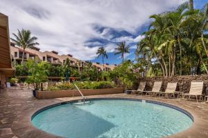 a swimming pool at a resort with chairs and trees at Kamaole Sands 7-100 in Wailea