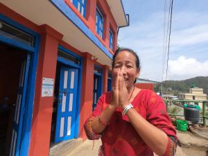 kobieta stojąca przed budynkiem w obiekcie Namaste Home Stay w mieście Dhulikhel