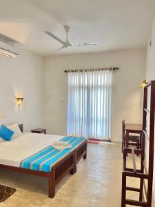 a bedroom with a bed and a window at Curry Bowl Restaurant & Turtles Rest in Hikkaduwa