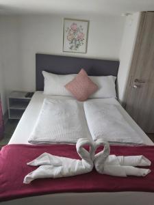 two towels in the shape of hearts on a bed at Panda Rooms in Maribor