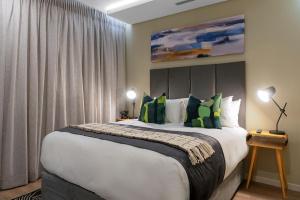 ein Schlafzimmer mit einem großen Bett mit grünen Kissen in der Unterkunft CAG The Hub Bryanston in Johannesburg