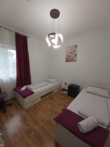 1 dormitorio con 2 camas y lámpara de araña en Panda Rooms, en Maribor
