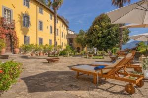 ein gelbes Gebäude mit Liegestühlen und einem Sonnenschirm in der Unterkunft Villa Raffaelli in Fosciandora