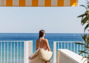 a woman standing on a balcony looking at the ocean at Belle Vue H&ocirc;tel in Cavalaire-sur-Mer