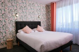 ein Schlafzimmer mit einem großen Bett mit rosa Kissen in der Unterkunft The Originals City, Hôtel Armen Le Triton, Roscoff in Roscoff