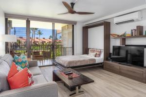 a living room with a couch and a flat screen tv at Kamaole Sands 3-303 in Wailea