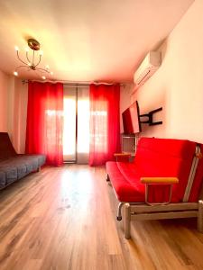 sala de estar con cortinas rojas y sofá rojo en PORT AMBAR - Apartamento en la Marina de Empuriabrava - balcón con vistas al canal - playa - wifi, en Empuriabrava