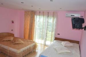 une chambre avec deux lits et une télévision au mur dans l'établissement Vila Denisa, à Eforie Nord