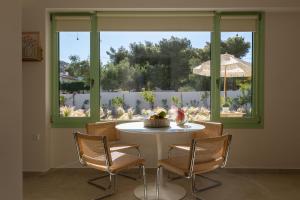 a table and chairs in a room with a large window at Kallisti Stay in Artemida