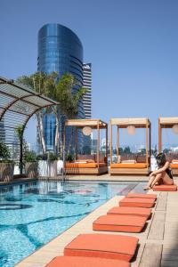 a woman sitting on a pool at a hotel at The George Tel Aviv in Tel Aviv