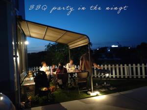 a group of people sitting at a table under a tent at Villa上条 名古屋から30分本格ガスグリルでBBQができる宿 in Kasugai
