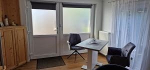 a room with a table and chairs and windows at Slaapstuuv in Greetsiel