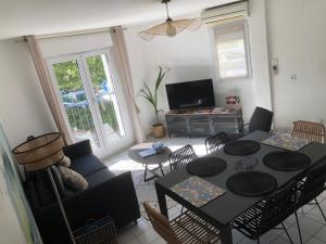 ein Wohnzimmer mit einem schwarzen Tisch und Stühlen in der Unterkunft Maison de ville proche mer in Les Sables-dʼOlonne