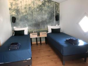 zwei Betten in einem Zimmer mit blauen Laken und einem Tisch in der Unterkunft Maison de ville proche mer in Les Sables-dʼOlonne
