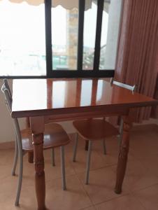 una mesa de madera con 2 sillas frente a una ventana en Vila Aliaj beautiful room for 2 with air conditioning, en Durrës