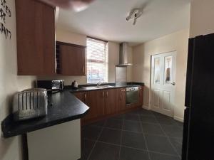 a kitchen with wooden cabinets and a black counter top at 82a Underwood Lane in Crewe