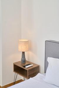 eine Lampe auf einem Nachttisch neben einem Bett in der Unterkunft STUDIO Apartment Lugano SeaUAthens in Athen