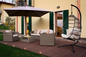 eine Terrasse mit einem Sonnenschirm, Stühlen und einer Schaukel in der Unterkunft SalvatoreHomes - Luxury Villa with private Garden & BBQ in San Zeno di Montagna