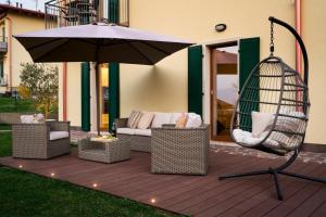 a patio with an umbrella and chairs and a swing at SalvatoreHomes - Luxury Villa with private Dream Garden & BBQ - Casa Palma - a 5 Star Luxury Collection at Lake Garda in San Zeno di Montagna