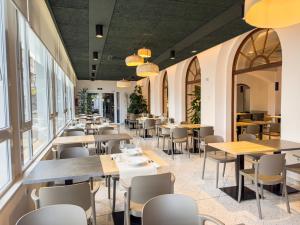 een restaurant met tafels, stoelen en ramen bij Hotel Marina in Roses