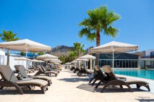a row of chairs and umbrellas next to a swimming pool at Paradice Hotel Luxury Suites-Near zorbas Beach-FREE Breakfast in Stavros