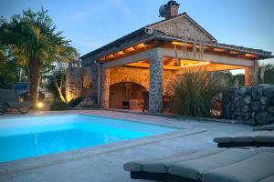 a swimming pool with a gazebo in a backyard at Vila na Kamenu in Dobrinj