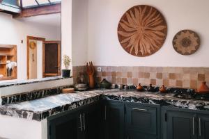 a kitchen with black cabinets and tiles on the wall at Surfiscamp Dakhla in Dakhla
